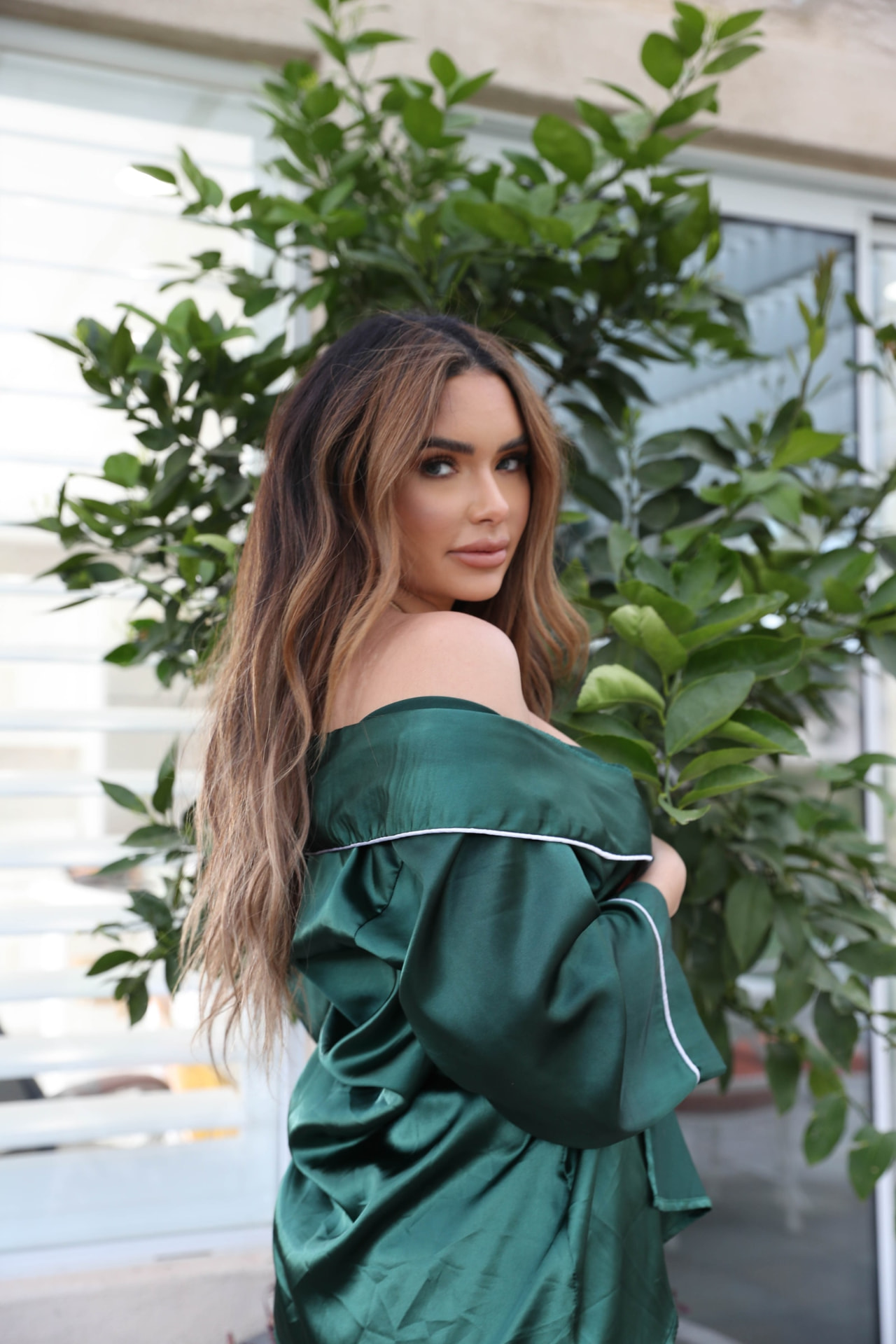 Over-the-shoulder view of a deep green look with white piping