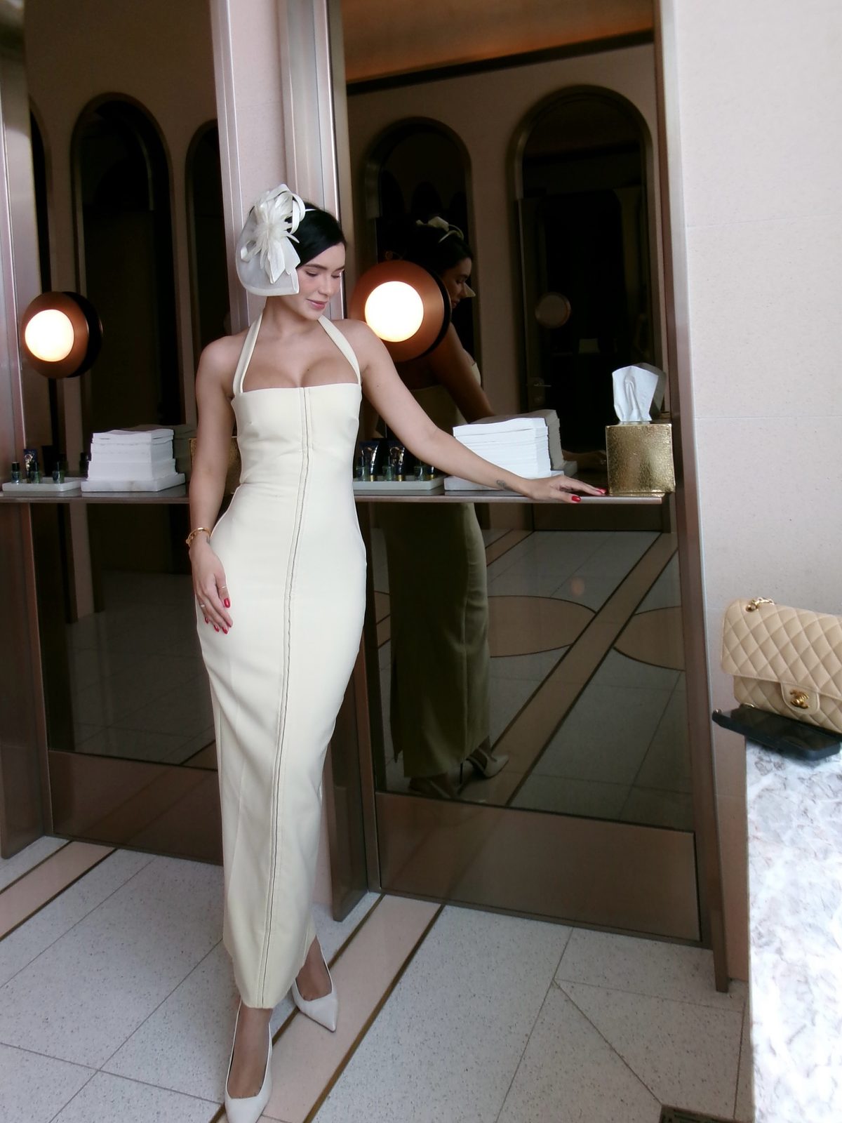 Jamillette in a white column dress and white headpiece in a doorway